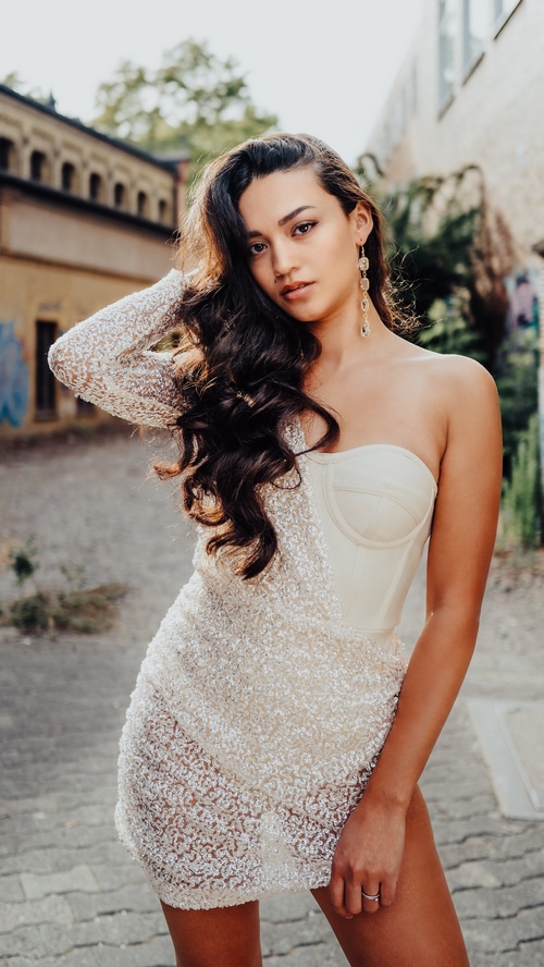 Woman in a white sequined dress posing outdoors