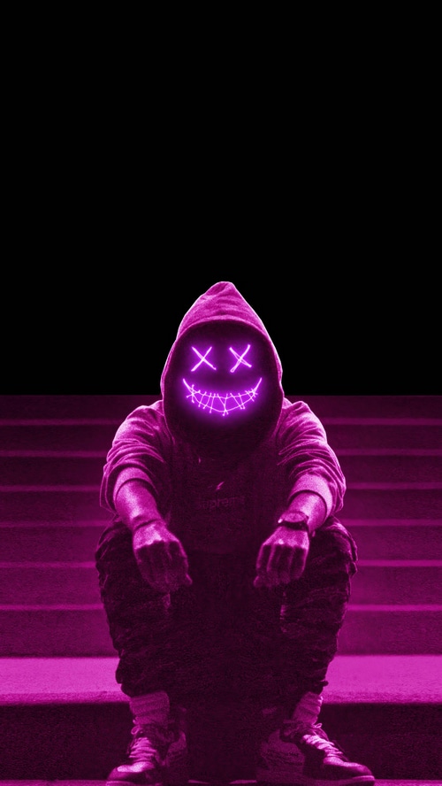 Person in a neon mask and hoodie sitting on stairs