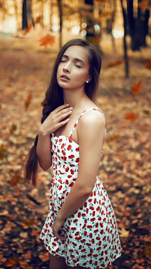 Young woman in a cherry-print dress in autumn park