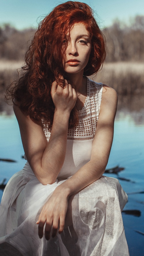 Redhead model posing by a lake