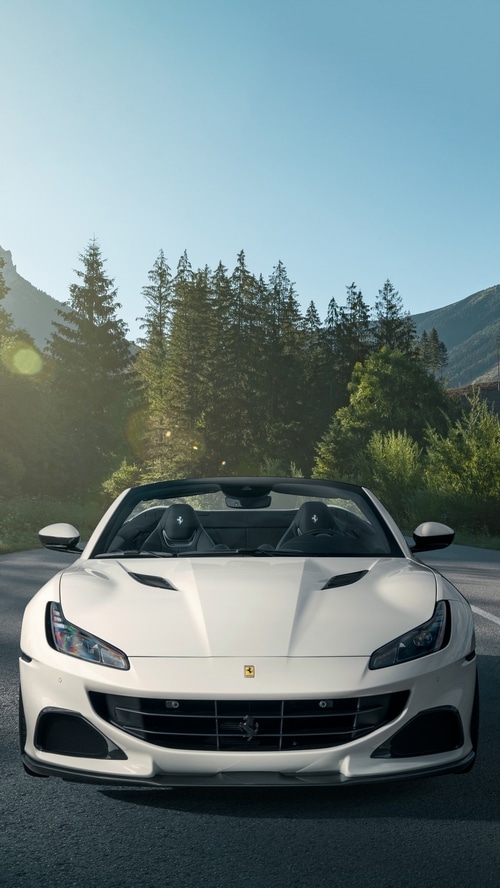 White Ferrari Portofino convertible driving on a mountain road