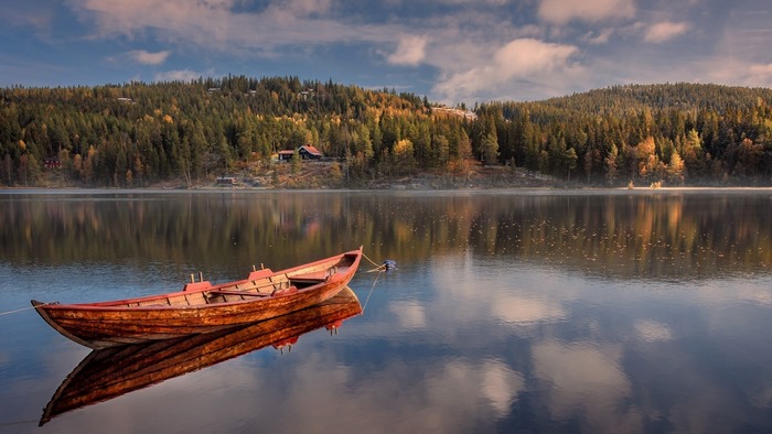 Wooden boat on a calm lake with forested hills