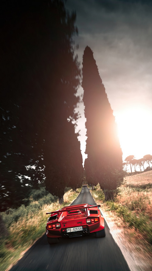 Red Lamborghini Countach driving on a road