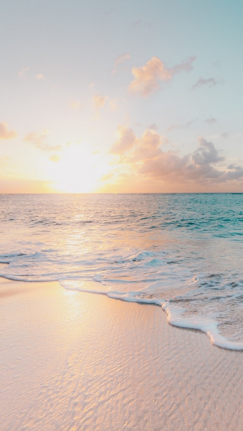 Sunrise over the ocean with gentle waves on the shore