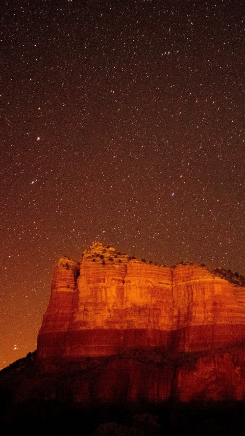 Red rock formations under a starry night sky