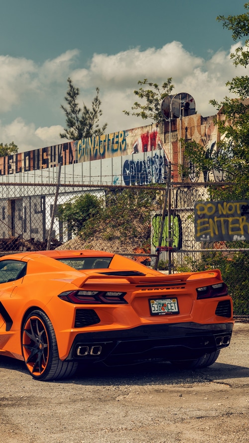 Orange Chevrolet Corvette parked near graffiti wall