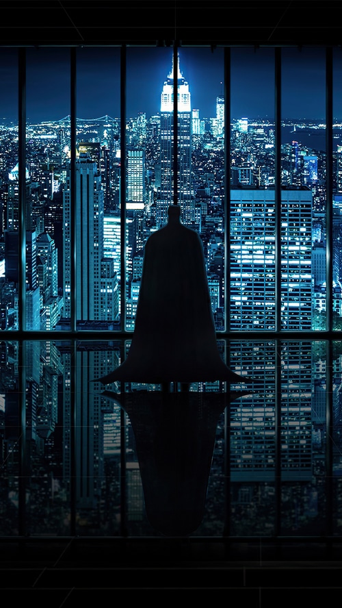 Batman standing in front of a city skyline at night