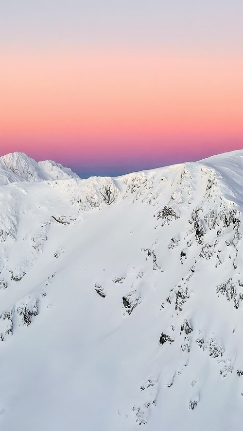 Snowy mountains under a pink and purple sky