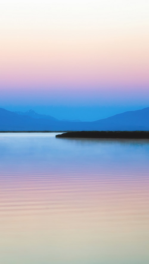Mountains silhouette over a calm lake at sunset