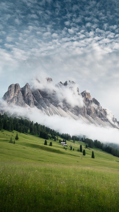 Mountains in Italy with clouds and green fields