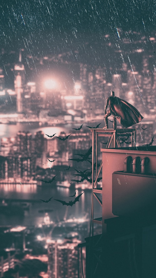 Batman standing on a rooftop with bats flying
