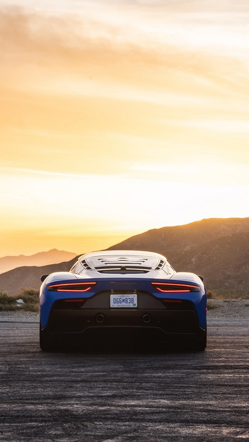 Blue Maserati MC20 rear view at sunset