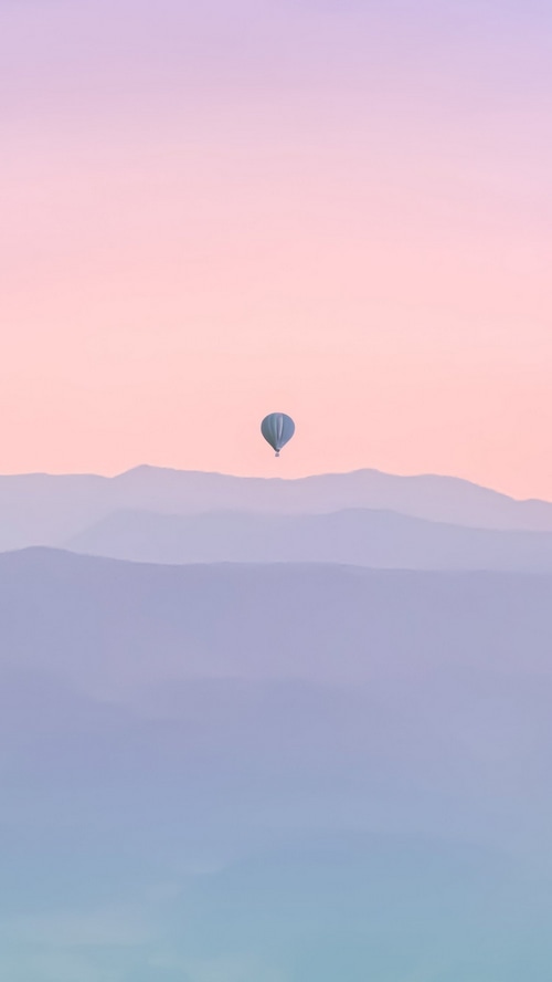 Hot air balloon over misty mountains at sunrise