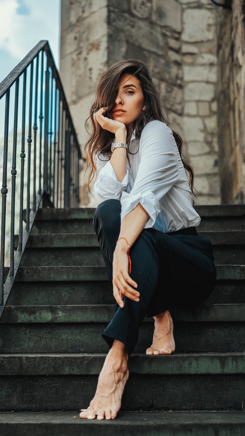 Woman in white shirt and black pants sitting on stairs