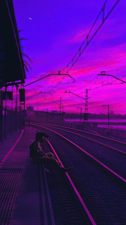 Person sitting on a train platform at sunset