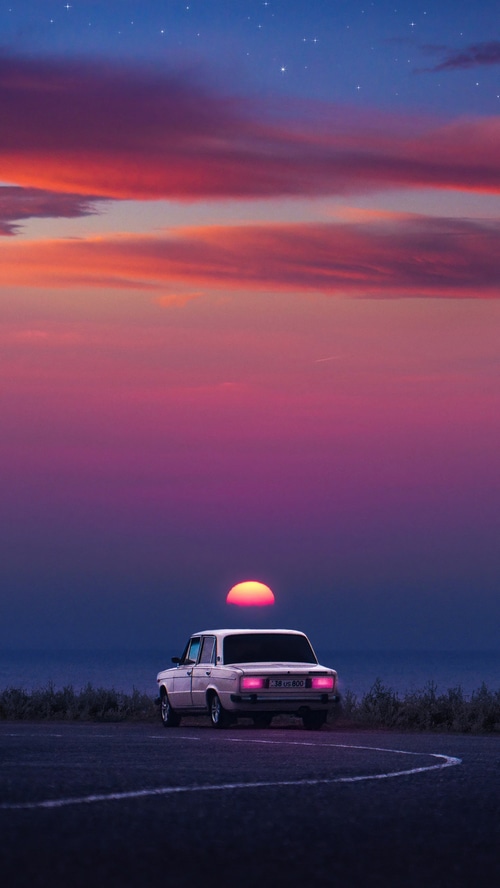 Car parked by the sea at sunset