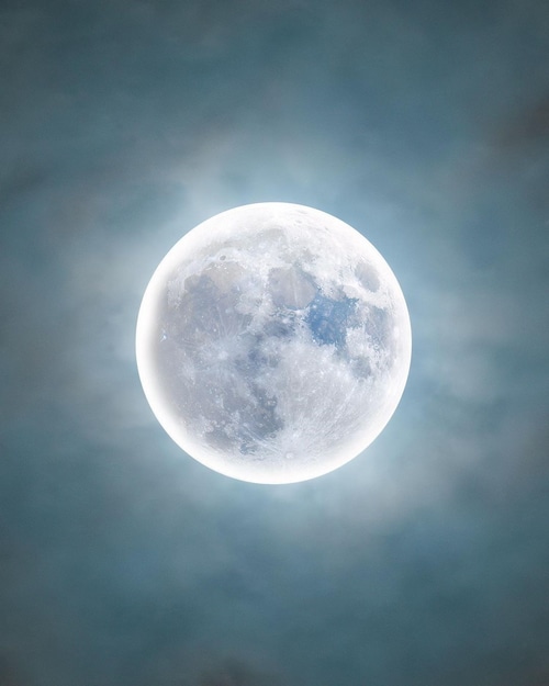 Full Moon glowing through clouds at night