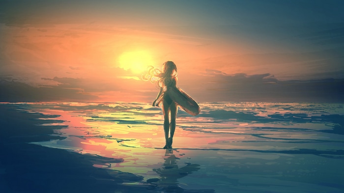 Woman standing on a beach at sunset with hair blowing