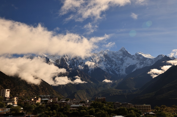 Snowy mountains in Tibet with clouds and a village