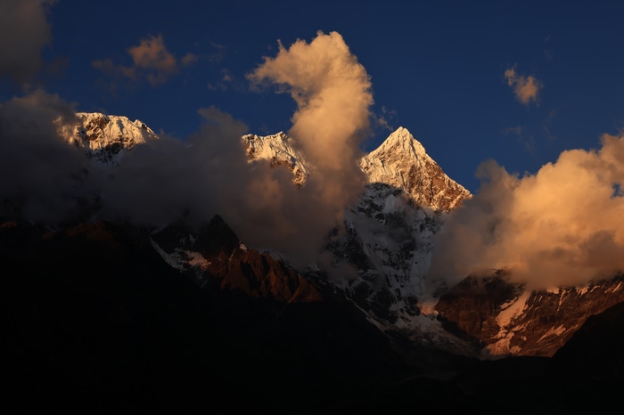 Snowy peaks in Tibet at sunset with clouds