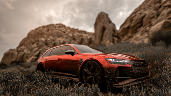 Red Audi RS6 Avant in a rocky, grassy landscape