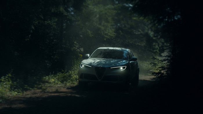 Alfa Romeo Stelvio driving through a dark forest
