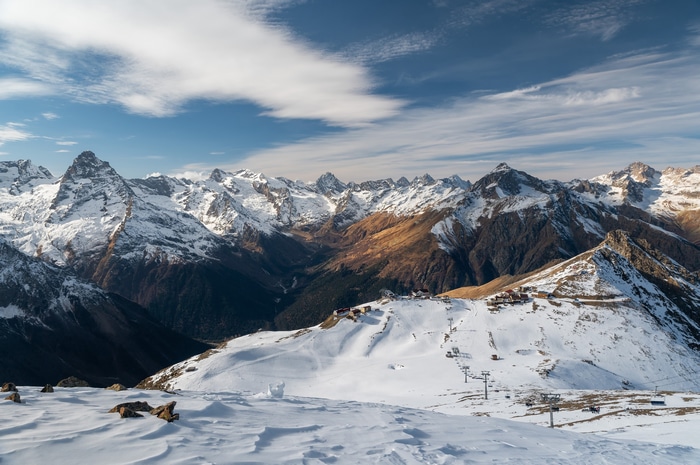 Snow-covered mountains under a cloudy blue sky