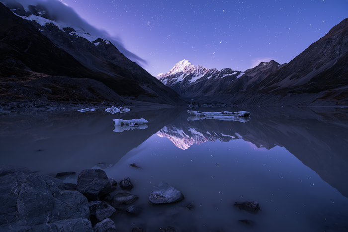 Mount Cook reflected in a lake under a starry sky