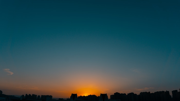 Sunset over city skyline with silhouette buildings