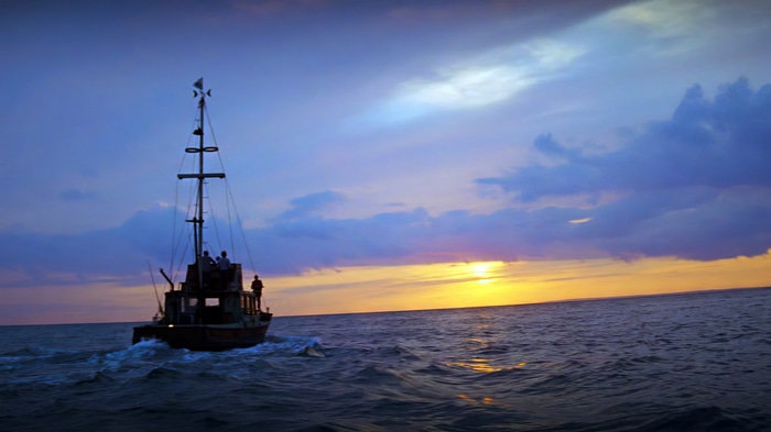 Boat sailing at sunset with dramatic clouds