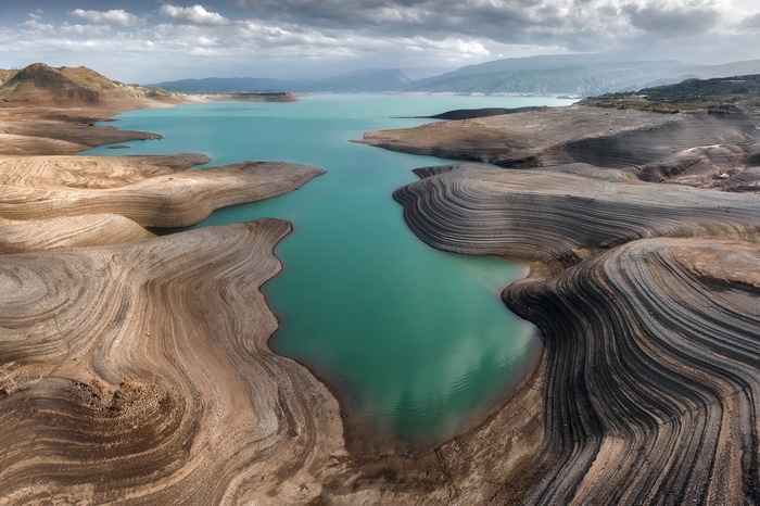 Reservoir landscape with turquoise water and dry, layered shores