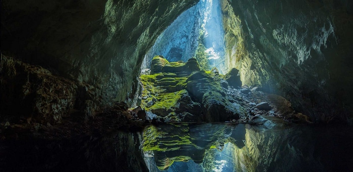 Hang Son Doong cave with mossy rocks and lake reflection