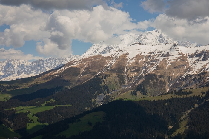 Snow-capped mountains and green valleys under a cloudy sky