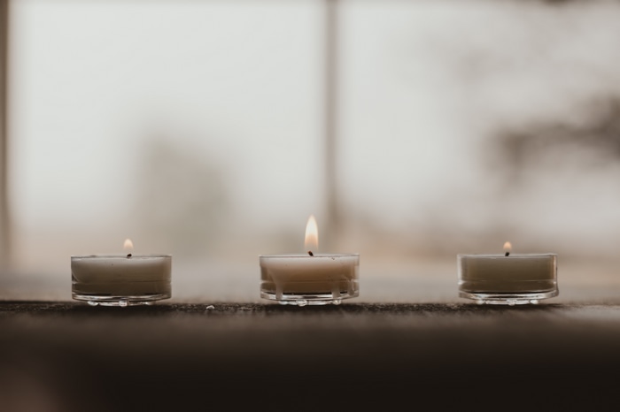 Three lit tea candles with a blurry background