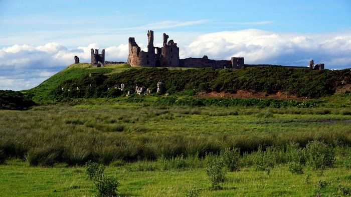 Dunstanburgh Castle ruins on a grassy hill in Northumberland