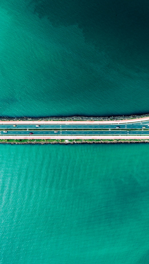 Aerial view of a highway bridge over turquoise water