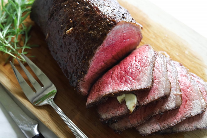 Sliced roast beef with garlic on a cutting board