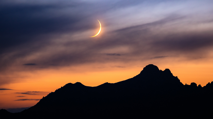 Crescent Moon Over Silhouetted Mountains at Sunset