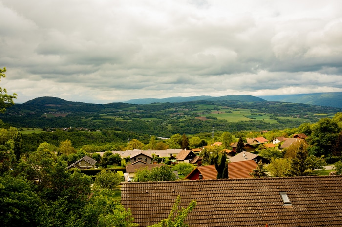 Village nestled in rolling green hills under cloudy sky