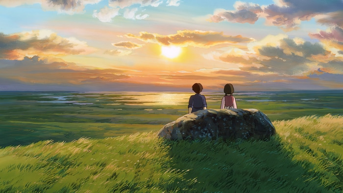 Two people watch the sunset over a grassy field