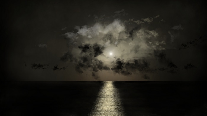 Moonlight reflecting on the ocean through clouds