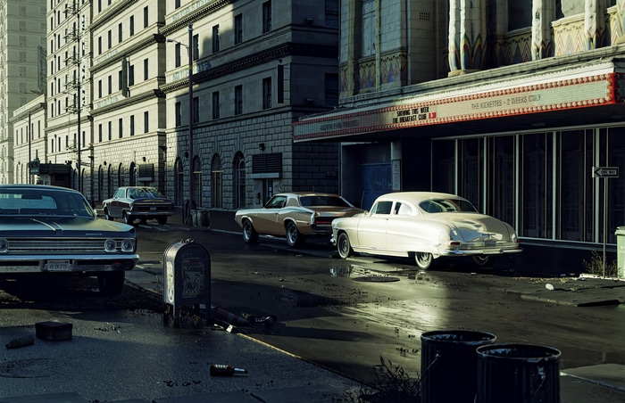 Vintage cars parked on a city street in front of a theater