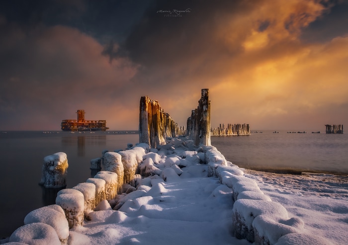 Winter pier and abandoned building at sunrise