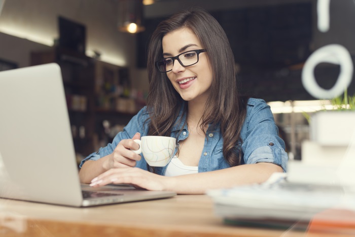 Woman with Glasses and Coffee Cup on Laptop