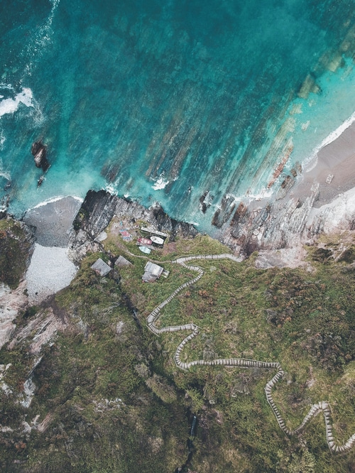 Aerial view of a winding path leading to a secluded cove in Asturias, Spain