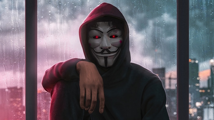 Anonymous hacker in a hoodie with glowing red eyes