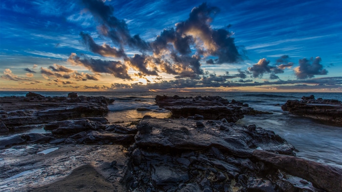 Sunset over rocky coast with dramatic clouds