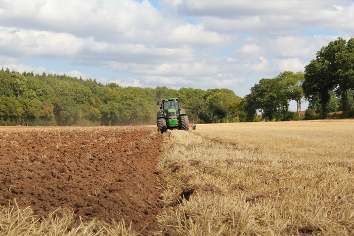 Tractor plowing a field with trees in the background