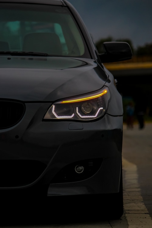 Frontal view of a black BMW car with illuminated headlights