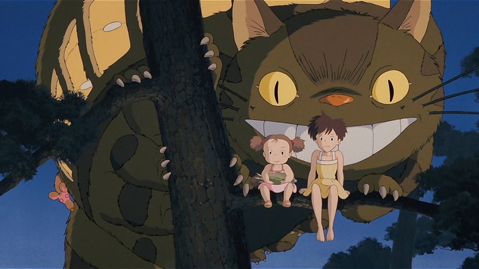Totoro and two girls sitting on a tree branch